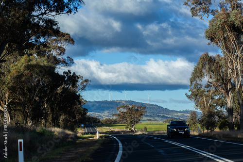 rural road through farmland countryside with wind farm on horizon