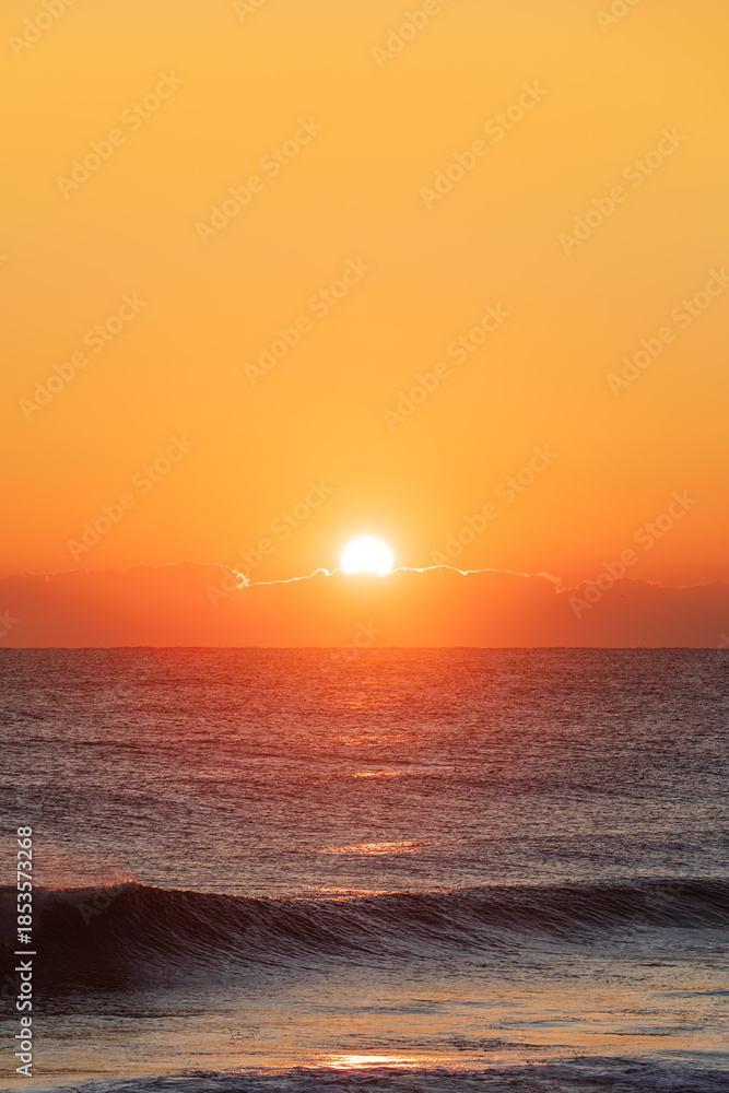 Obraz premium Sunrise Light Behind Low Clouds Over the Ocean