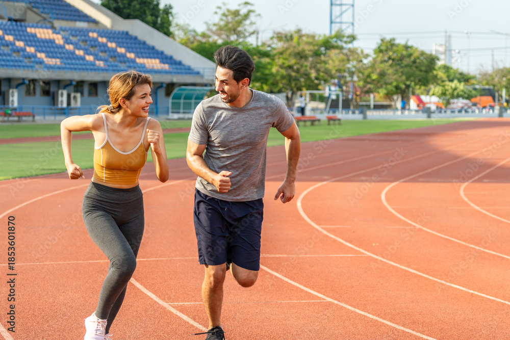 Fototapeta premium Diverse young man and woman running exercising together at stadium.