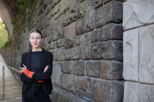 Self-confident urban teenage girl standing by stone wall in Aachen