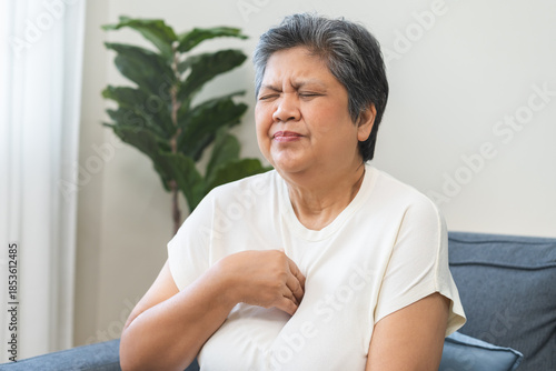 Foto Acid reflux disease, suffer asian aged woman have symptom gastroesophageal, esophageal, stomach ache and heartburn pain hand on chest from digestion problem after eat food, Healthcare medical concept