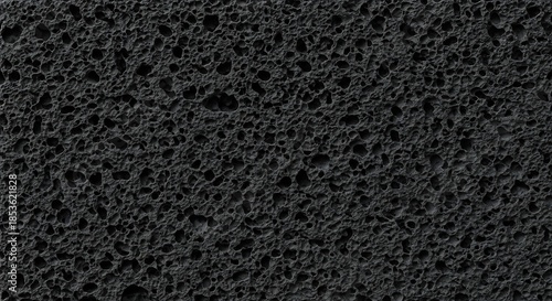 Dark porous volcanic rock texture with irregular holes and rough surface, abstract background