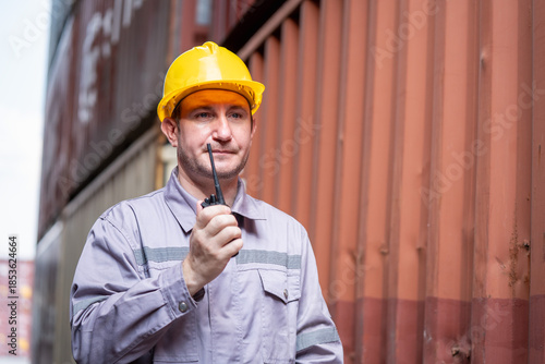 Warehouse worker communicates with radio device at shipping yard industrial environment close-up view logistics concept