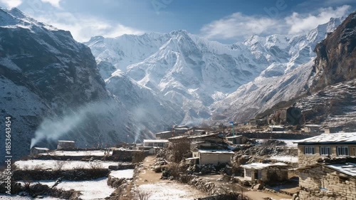 4K Traditional stone houses in a himalayan village nestled in a valley surrounded by massive snowcovered mountains under a bright blue sky video