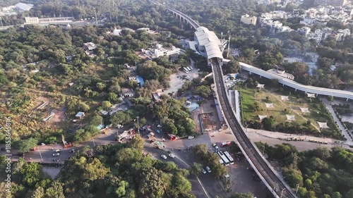 Aerial view of Nehru Place Metro Station, New Delhi, showing elevated Delhi Metro tracks cutting through dense green cover, busy road intersections, and surrounding urban neighborhoods of South Delhi.
