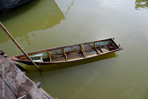 Obraz na płótnie Traditional Wooden Boat Moored on Calm Green Water,