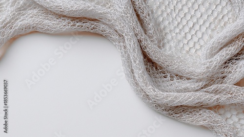 Textured gray mesh fabric draped elegantly on a smooth surface, showcasing intricate patterns and soft light, ideal for creative design and artistic projects with copy space