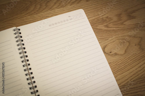 Blank spiral notebook page on wooden table with copy space for text.