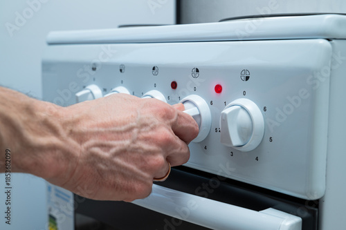 A woman's hand turns on the electric stove using a knob