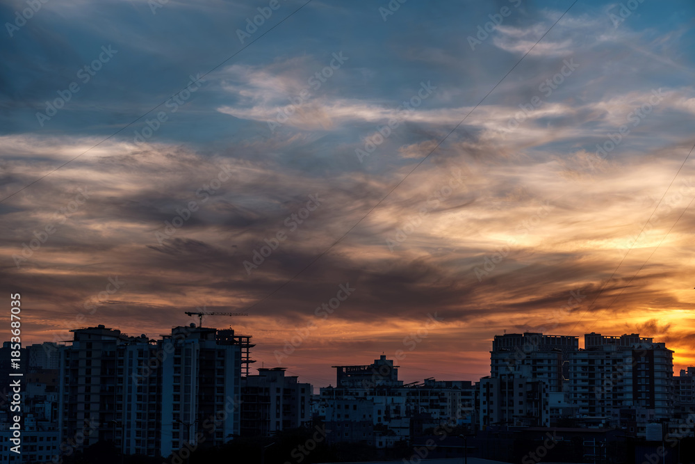 Fototapeta premium Evening scene with lit up and silhouetted buildings against a colourful evening sky at Pune India.