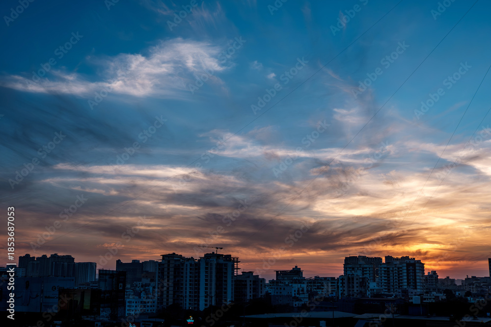 Fototapeta premium Evening scene with lit up and silhouetted buildings against a colourful evening sky at Pune India.