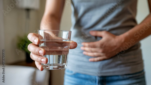Person Holding Glass of Water with Stomach Pain Concept