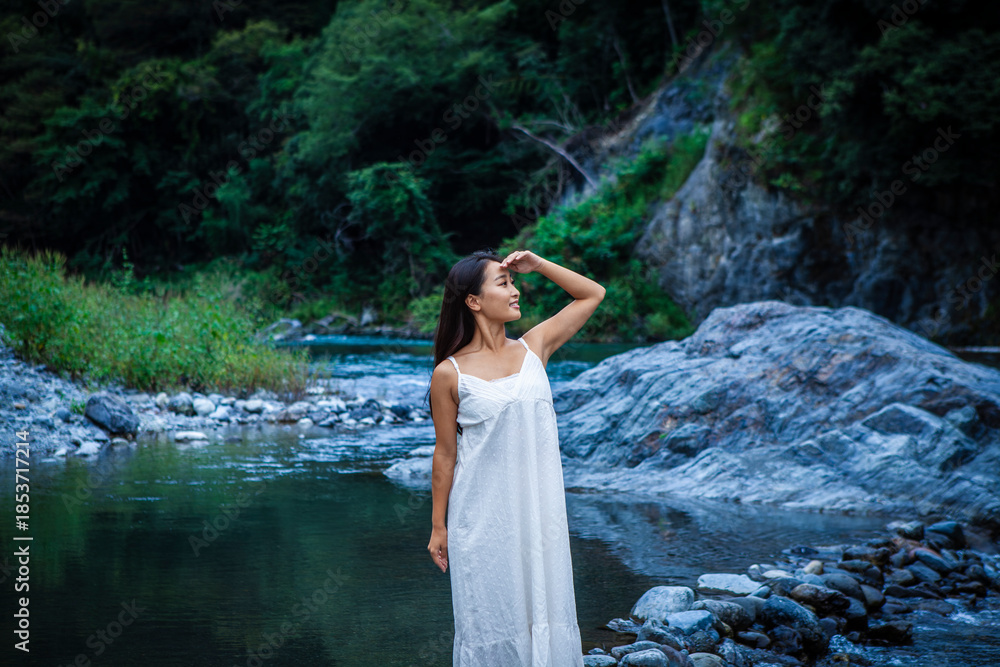 Fototapeta premium Thoughtful Woman Enjoying Quiet Moments by a Clear Mountain River