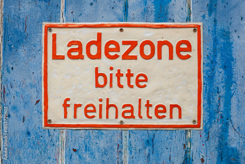 Ates Schild Ladezone freihalten  an einem alten, blauen Garagentor, Deutschland