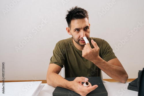 Portrait of young man applying medical patch to injured finger, demonstrating self-care for minor hand wound at home, preventing infection and managing discomfort after accident.