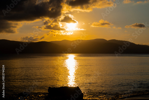 Dramatic Golden Sunset Over Ocean and Mountain Silhouettes
