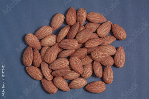 Almonds rest on a simple piece of paper, highlighting their natural texture in a clean minimal scene.