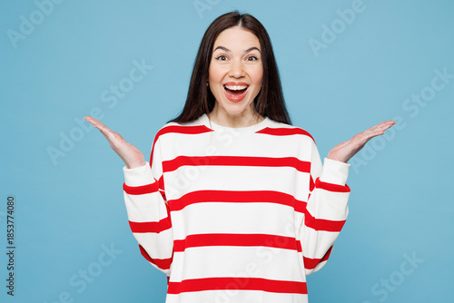 Quadro su tela Young shocked surprised happy Caucasian woman she wear red striped sweatshirt casual clothes look camera spread hands isolated on plain pastel light blue background studio portrait
