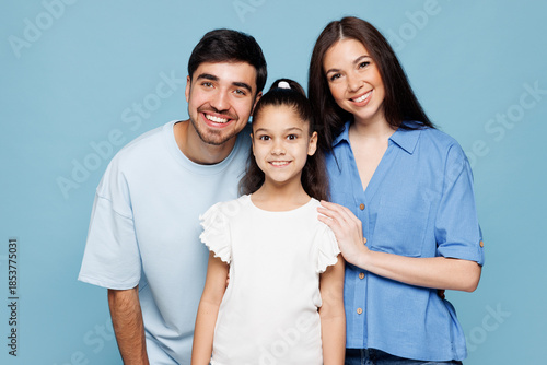 Bilde på lerret Young smiling fun happy parents mom dad with child kid daughter girl she wear casual clothes look camera embrace hug posing isolated on plain blue background