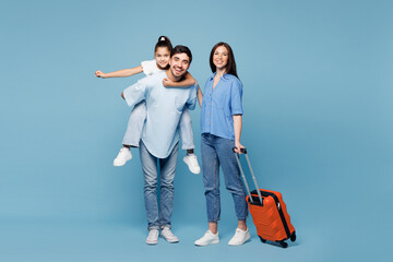 Traveler young fun parents mom dad child wear casual clothes hold suitcase bag isolated on plain blue background. Tourist travel abroad in free spare time rest getaway Air flight trip journey concept