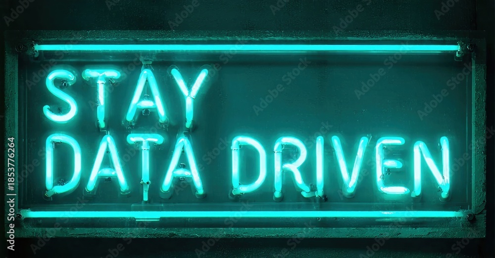 Obraz premium Bright neon sign displays text Stay Data Driven. Dark background emphasizes glowing turquoise illumination. Simple rectangular frame surrounds message.