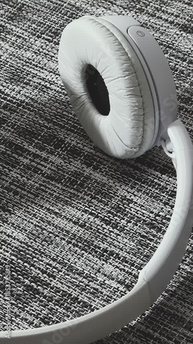 White headphones placed on a textured black and white table surface in a cozy indoor setting