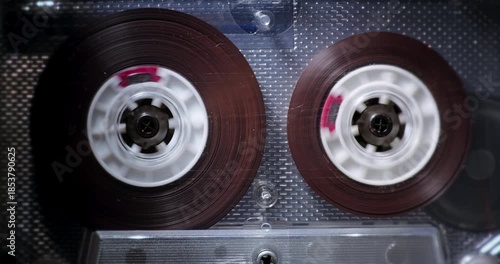 Close-up of transparent audio cassette. Audio Cassette Fast Rewind. Transparent compact cassette with brown tape rewinding at high speed.