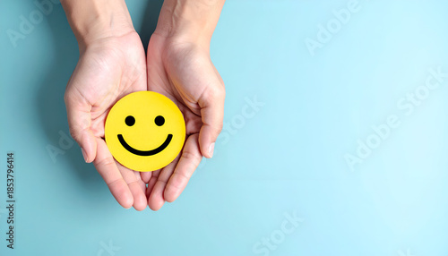 Human hands protecting a happy emoji, concept of mental health, kindness, and emotional well-being.