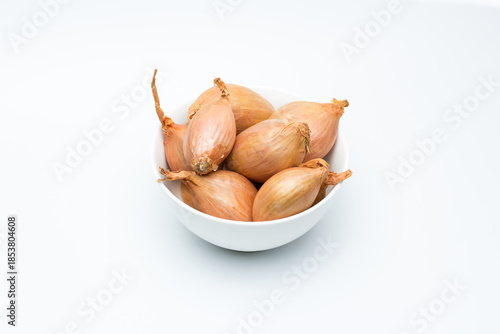 Chalotas frescas en cuenco blanco sobre fondo blanco