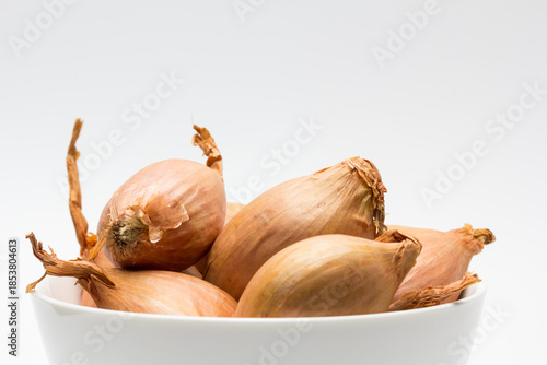 Chalotas frescas en cuenco blanco sobre fondo blanco
