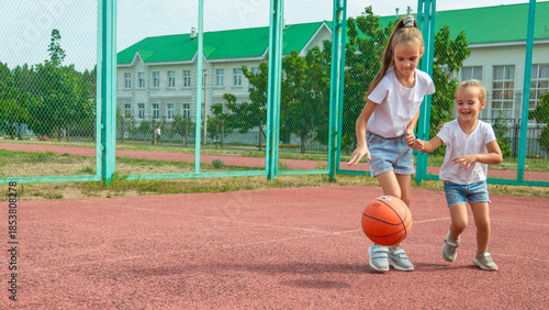 summer vacation, sport, games and friendship concept - happy children playing basketball outdoors