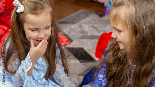 A happy little girls in a beautiful blue dress sitting in festive Christmas interior with a gifts and cheerful laughing.