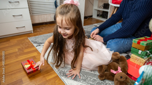 Happy father and daughter opening Christmas gifts together and smiling. Holidays concepts