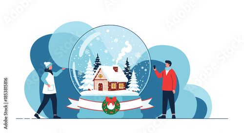 A man and a woman in winter clothes stand next to a giant snow globe containing a cozy house in a snowy landscape for Christmas.
