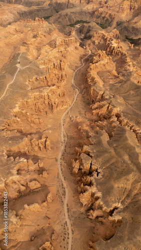 Aerial view of rugged desert landscape with distinctive rock formations and winding road cutting through terrain