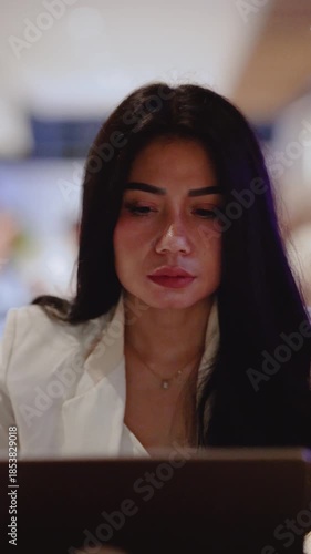 Close-up view of a serious young woman using her laptop while sitting at the cafe. Vertical video.
