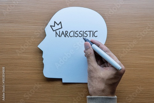 Photos A hand writes NARCISSISTIC with a crown inside a paper head profile