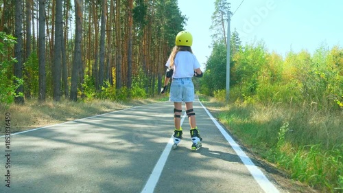 Girl is roller skating by forest, enjoying an active hobby in the open air.