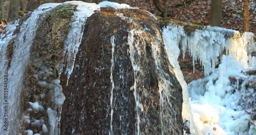 Wallpaper Mural An image showing a rock covered in ice. The rock has water flowing over it, and there are icicles hanging from it. The ice is clear and sparkling, and the rock is dark and rugged. Winter's touch. Torontodigital.ca