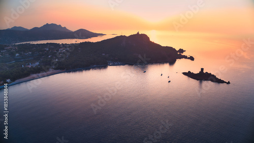 Aerial view of a golden sunrise illuminating the Mediterranean sea, casting a warm glow over the coastline near ÃŽle d'Or and Cap Dramont, St RapahaÃ«l, France.