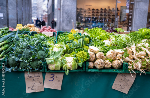 Fresh green vegetables including broccoli lettuce cauliflower and root vegetables on display at outdoor market stall