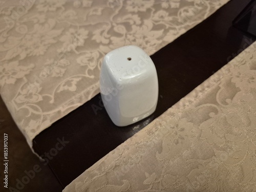 A salt shaker stands on a table in a restaurant