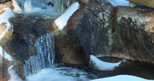 Wallpaper Mural A miniature waterfall cascades over snow-covered rocks, creating a serene winter landscape. The icy formations add a touch of magic to the scene. High Tatras National Park, Slovakia, Europe. Torontodigital.ca