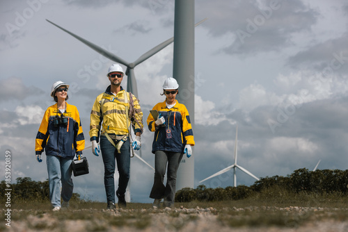 Team of wind turbine technicians wearing safety gear walking confidently at wind farm, symbolizing teamwork, clean energy industry, professional field operations.