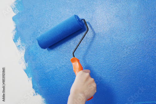 Roller Brush Painting, Worker painting on surface wall Painting apartment, renovating with blue color paint. Leave empty copy space white to write descriptive text beside.	
