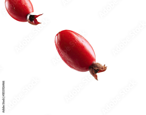 Two glossy, oblong, red rosehips isolated on a solid black background