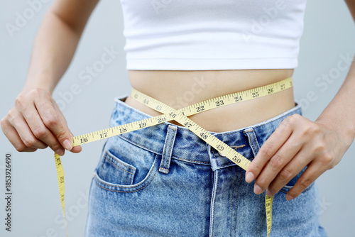 woman want to lose weight taking measurements of her body. and diet measuring waist with measure tape after diet weight control.