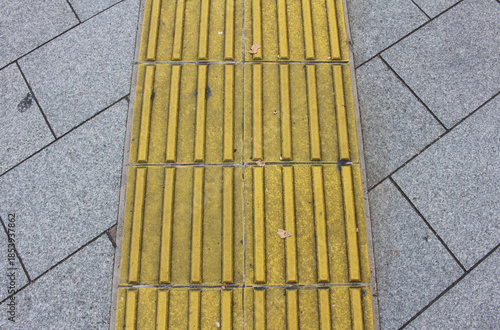 Wallpaper Mural Yellow blocks of tactile paving for blind handicap. Tactile pavement for the visually impaired close up background. Texture of gray square paving tile with Braille blocks in winter. Torontodigital.ca