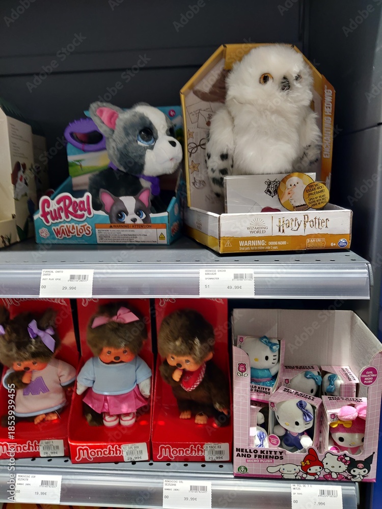 Fototapeta premium Saintes, France - December 17, 2025: Joue Club. Colorful display of various plush toys including FurReal, Harry Potter owl, and Hello Kitty characters in a retail store setting
