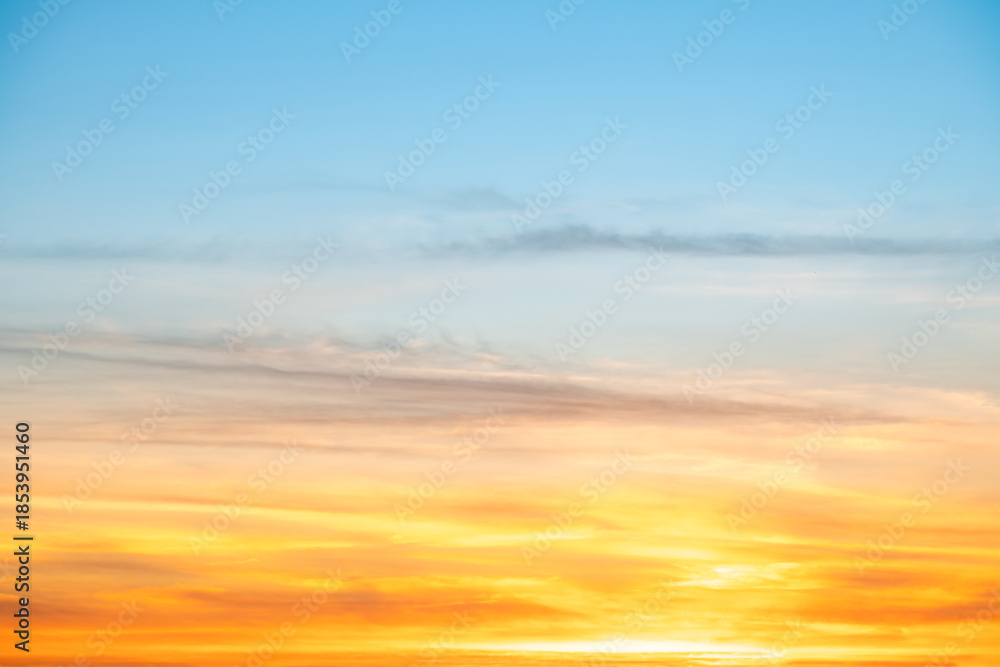 Fototapeta premium Sunset or sunrise sky with a vibrant gradient of orange, gold, and soft blue. Clear atmosphere with wispy clouds. Peaceful, natural light background. hope, freedom, new day and inspirational Concepts